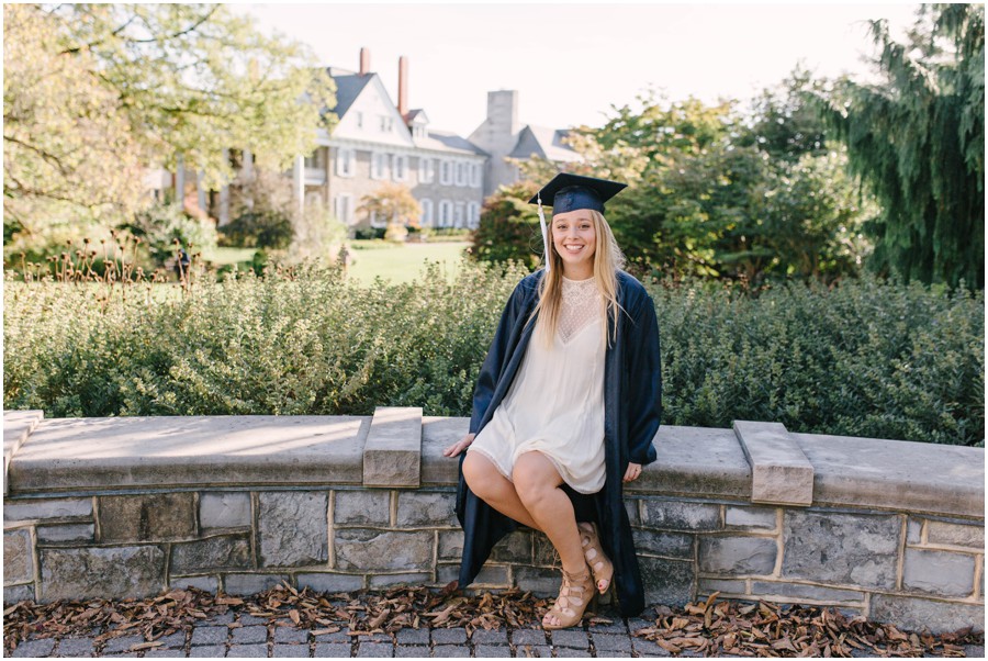 penn state university senior sitting on wall in gown